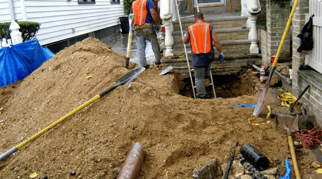 Contractors performing foundation protection and exterior drainage excavation near residential home steps in Norfolk, VA